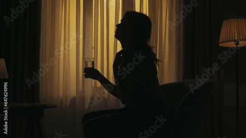 Everyday life creative concept. Woman sitting on a chair holding glass of water, feeling unwell because of heat.