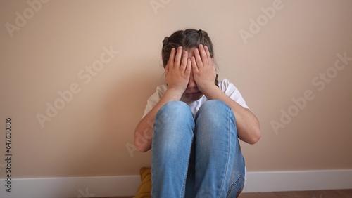 sad girl sitting in the corner crying a covered her face with her hands. family violence abuse child concept. parents punished the child put in a corner. child in lifestyle depression crying indoor