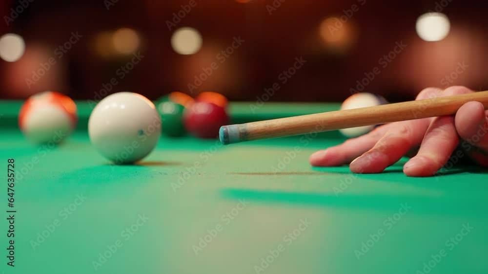 A young man plays Russian billiards, an American woman in a billiards club and bar. Dark colors in the billiard club. A man pockets snooker balls.