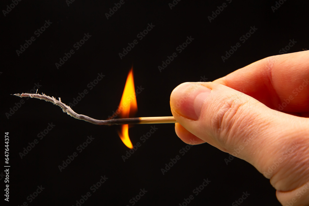 Fire and smoke. Burning match in hand on a black background. Heat and light from fire flame