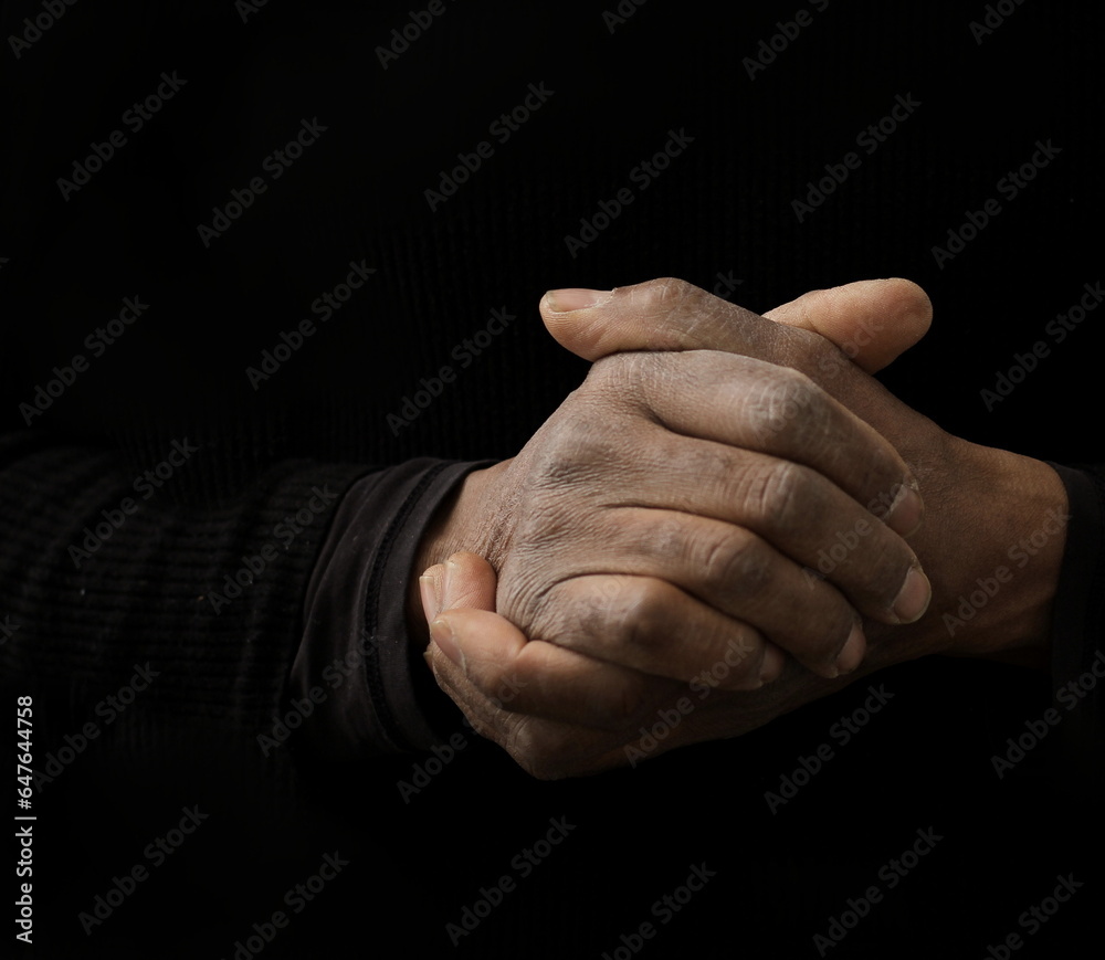 man praying to god with hands together on dark background with people stock image stock photo	