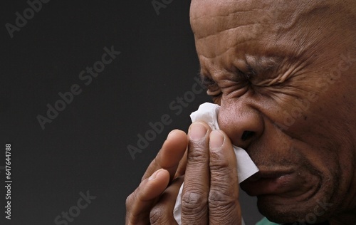 catching the cold and flu man blowing nose after catching a cold with grey background with people stock photo