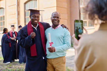 African American graduated student making photo with his family outdoors