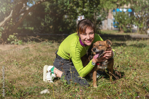 Dog with a volunteer. An animal shelter volunteer takes care of dogs. Homeless dog with a cheerful female volunteer.