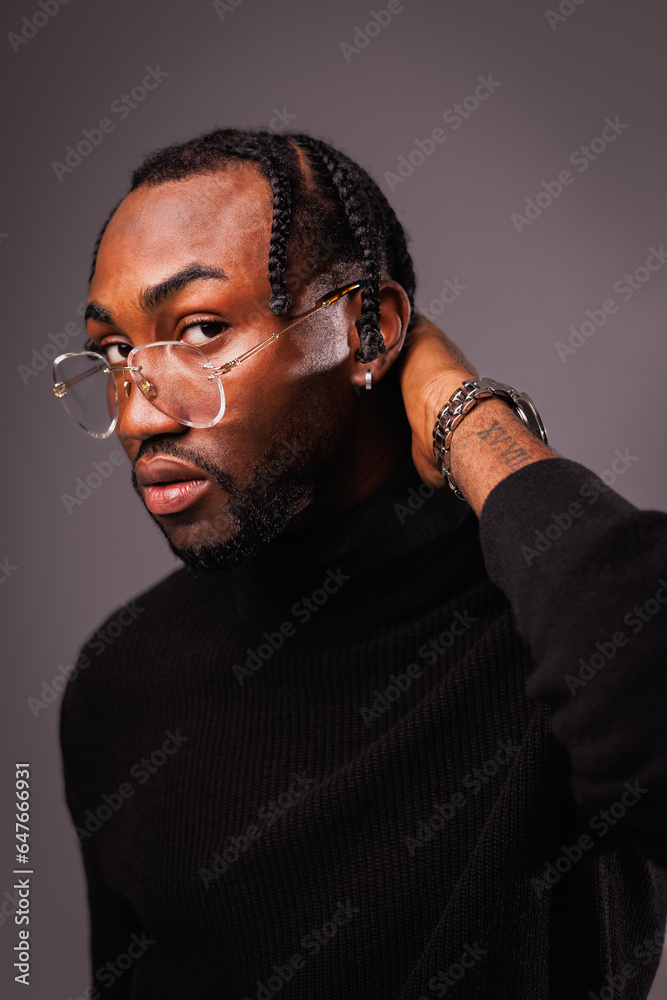 Portrait of stylish african american man in eyeglasses and black turtleneck touching neck and looking at camera isolated on grey Portrait of stylish african american man in eyeglasses and black turtleneck touching neck and looking at camera isolated on grey