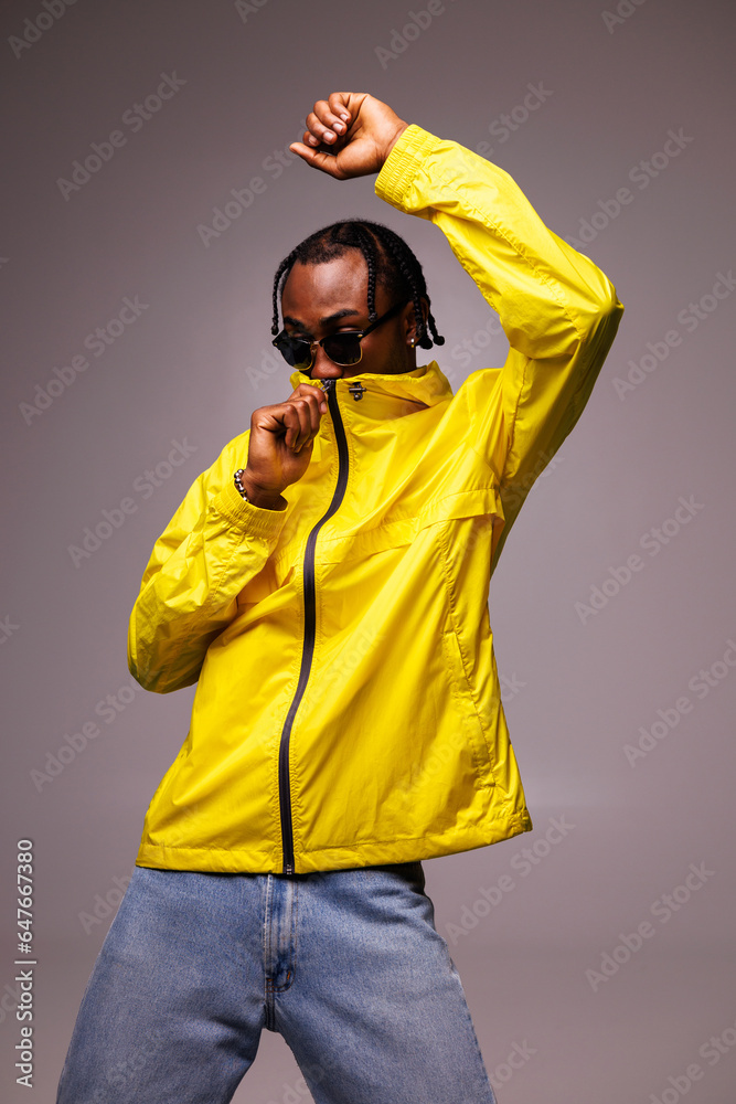 Stylish african american man in sunglasses and braids zip up windbreaker jacket isolated on grey Stylish african american man in sunglasses and braids zip up windbreaker jacket isolated on grey