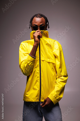 Young african american man with braids hairstyle wearing sunglasses and bright streetwear isolated on grey © Dmytro Hai
