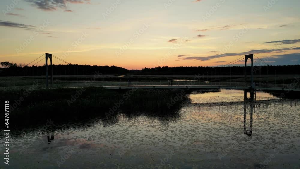 Aerial drone shot of a people walking on a bridge over a lake at sunrise, sunset Aerial drone shot of a people walking on a bridge over a lake at sunrise, sunset