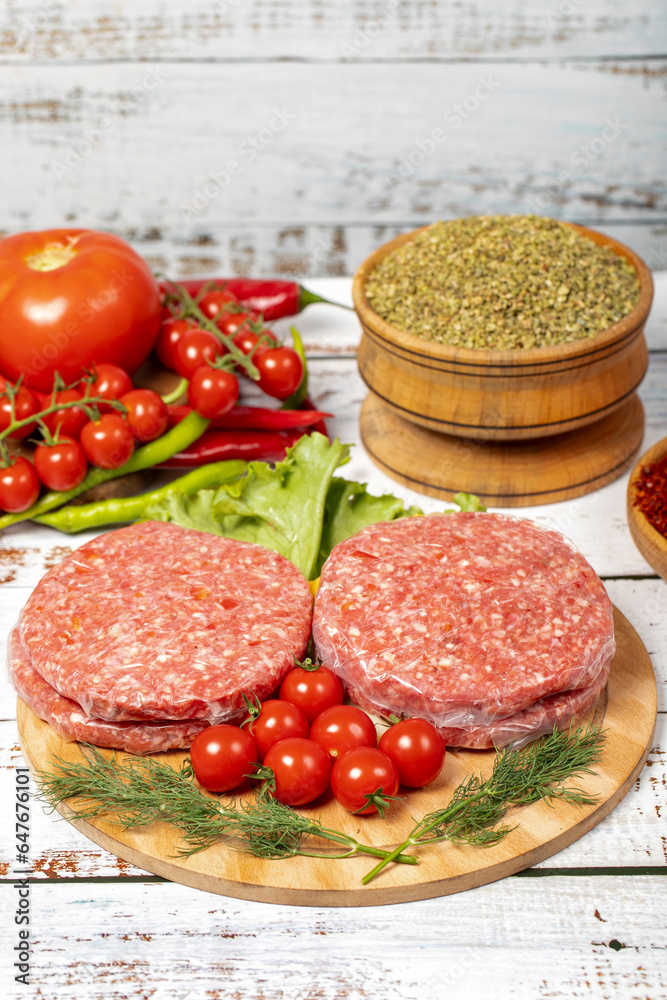 Raw hamburger patties on wood background. Raw veal hamburger patties with herbs and spices Raw hamburger patties on wood background. Raw veal hamburger patties with herbs and spices
