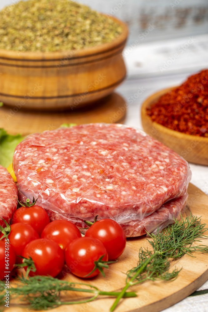 Raw hamburger patties on wood background. Raw veal hamburger patties with herbs and spices. Close up Raw hamburger patties on wood background. Raw veal hamburger patties with herbs and spices. Close up