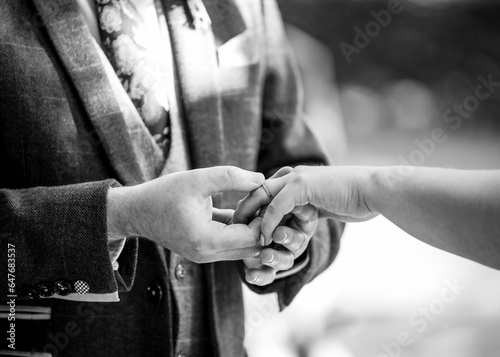 Groom placing beautiful wedding ring on to brides finger during wedding ceremony