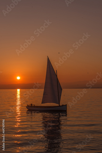 View of a sailboat sailing on the lake at sunset.