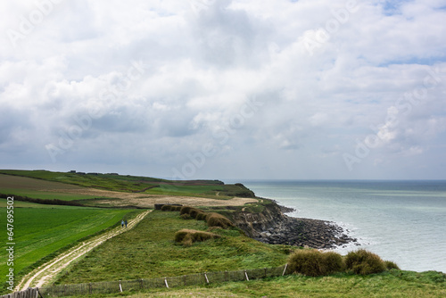 Sea, cliffs and two people walking  at a walking path on a green field   on the Opal Coast in northern France, seen at Cap Griz Nes on a sunny day with blue sky and clouds in April photo