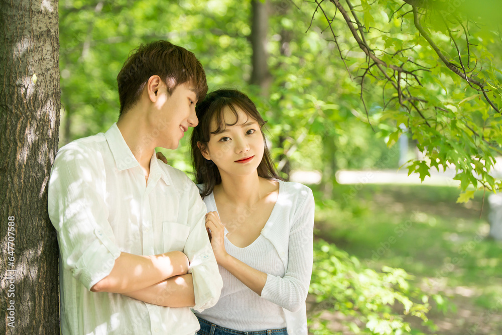 A lovely young couple are having fun in a forested park.