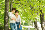 A lovely young couple are having fun in a forested park.