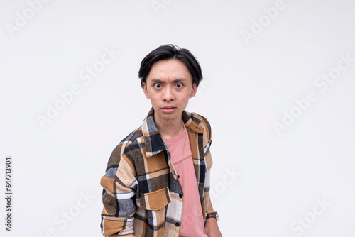 A young angry asian man looking very offended, with glaring bulging eyes. Isolated on a white background.