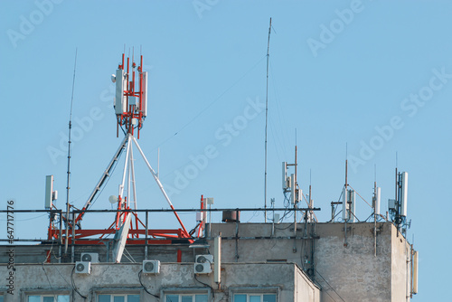 Fragment of a telecommunications tower against a blue sky with snow-white clouds.  Radio and satellite pole. Communication technology. Telecommunication industry. Mobile or telecom 4g network. 