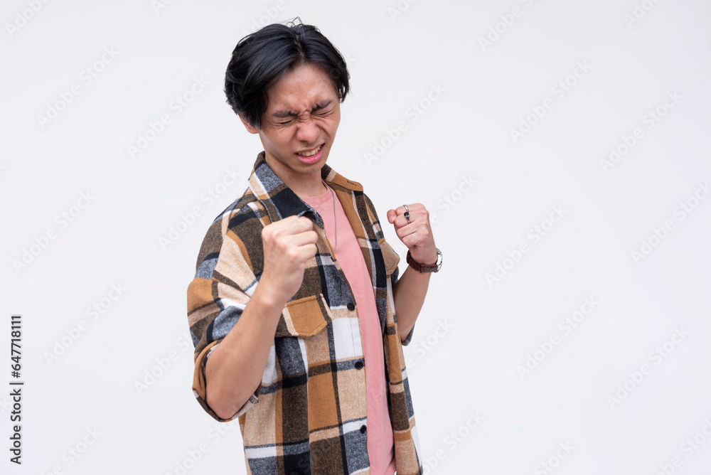 A triumphant young asian man celebrating, raising his hands up and pumping his fist. In a party mood. Isolated on a white background. A triumphant young asian man celebrating, raising his hands up and pumping his fist. In a party mood. Isolated on a white background.