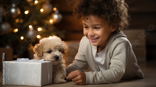 A boy plays with his puppy there are New Year's gifts and a Christmas tree in the background
