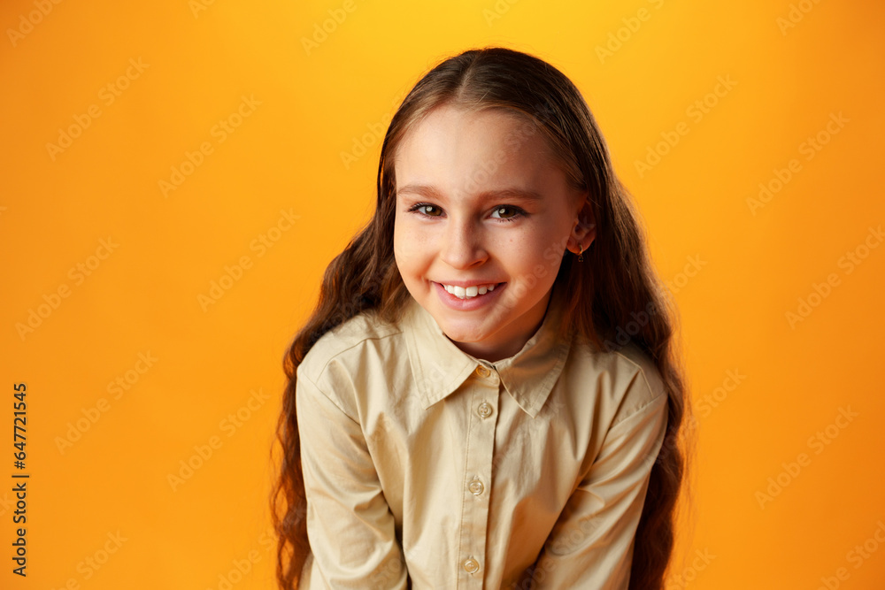 Photo of teen girl smiling portrait against yellow background in studio Photo of teen girl smiling portrait against yellow background in studio