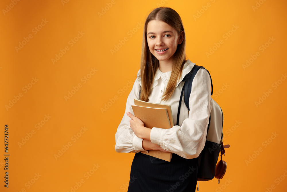 Teen girl in school uniform carry backpack on yellow background Teen girl in school uniform carry backpack on yellow background