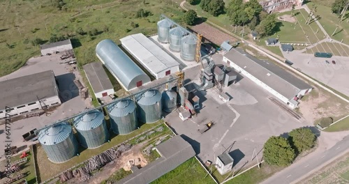 aerial view over modern granary elevator. Silver silos on agro-processing and manufacturing plant for processing drying cleaning and storage of agricultural products, flour, cereals and grain. 