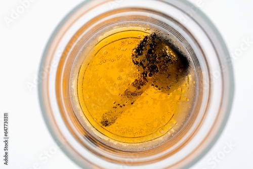 Looking Down Into A Partially Full Beer Glass With A Car Key On The Bottom Of The Glass photo