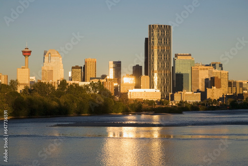 Calgary cityscape along river with reflections on building and river at sunrise with blue sky; Calgary alberta canada photo