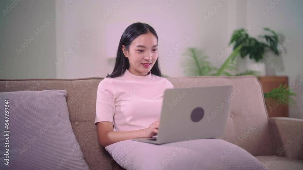 beautiful asian young woman wear casual sit on couch using computer laptop for working when relax in living room at home beautiful asian young woman wear casual sit on couch using computer laptop for working when relax in living room at home