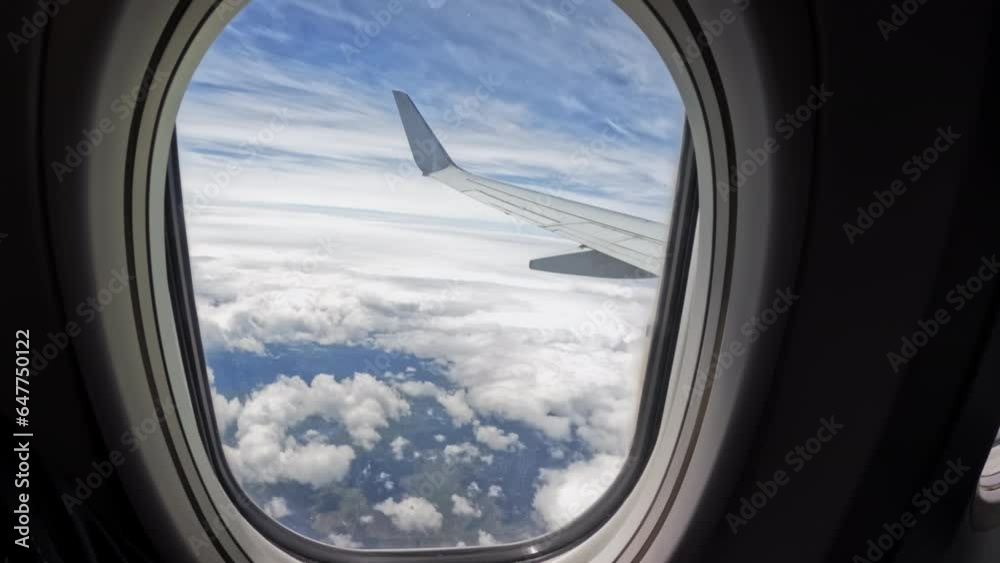 Aircraft plane Wing of flying in clouds and blue sky airplane as seen by passenger through porthole windows. Move camera Aircraft plane Wing of flying in clouds and blue sky airplane as seen by passenger through porthole windows. Move camera