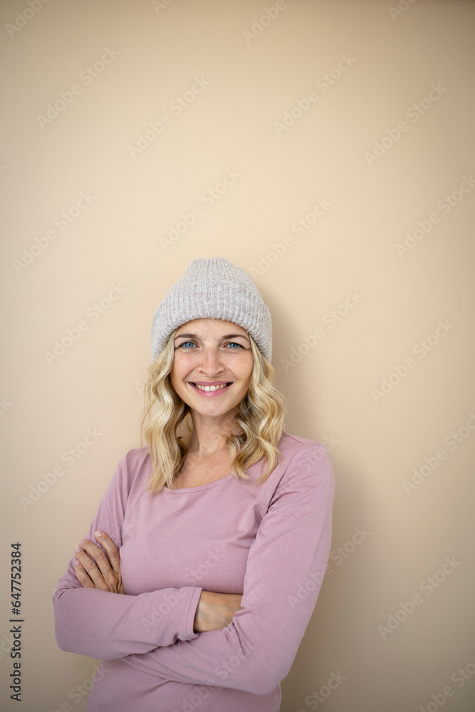 beautiful young woman with blond hair and grey cap, hood standing in front of brown background beautiful young woman with blond hair and grey cap, hood standing in front of brown background