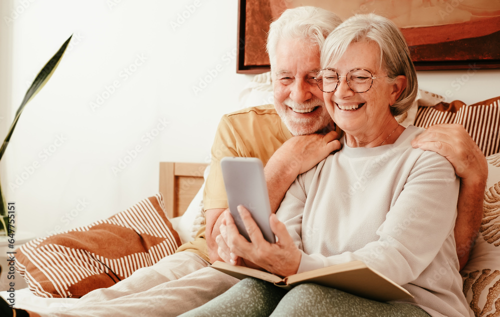 Video call concept. Portrait of happy handsome senior couple together in bed using phone webcam for video chat