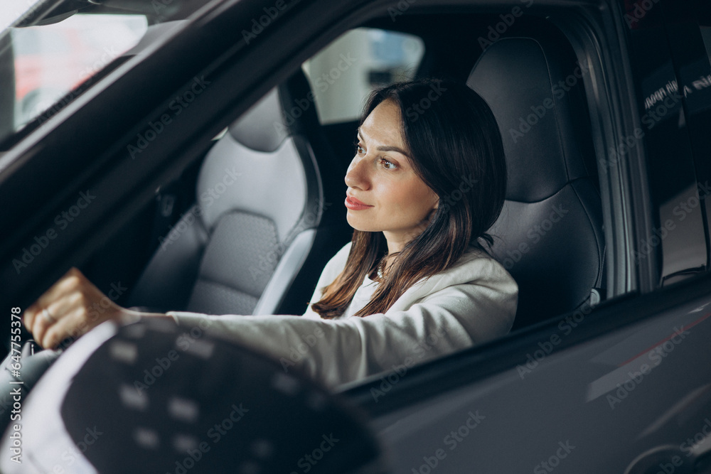 Woman sitting in her new car in a car showroom Woman sitting in her new car in a car showroom
