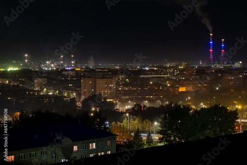 The night landscape of the city. Beautiful urban area with houses and boiler room at night. View of the big city from above. Smoking chimneys of boiler rooms on the background of the cityscape.