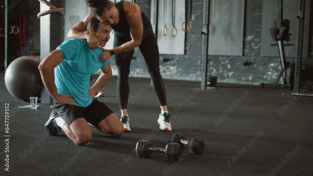 Female professional fitness instructor motivates tired man after cross fit training in gym