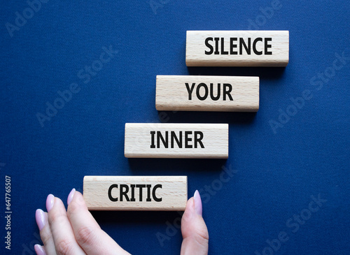 Silence your inner critic symbol. Wooden blocks with words Silence your inner critic. Beautiful deep blue background. Businessman hand. Business and Silence your inner critic concept. Copy space. photo