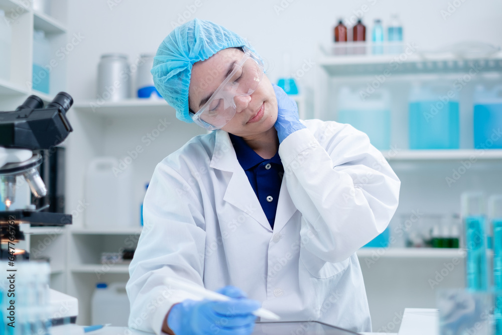 A tired female scientist working overtime in laboratory. Concept of exhausted, headache and stress while doing experiment, research or study in science area of workplace. A doctor work overload. A tired female scientist working overtime in laboratory. Concept of exhausted, headache and stress while doing experiment, research or study in science area of workplace. A doctor work overload.