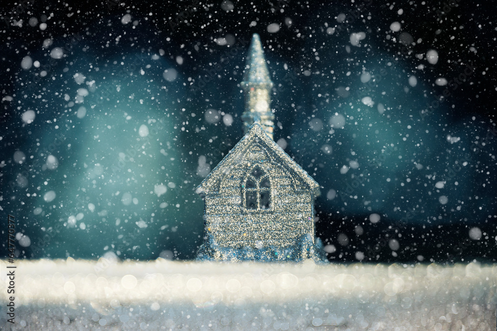 New Year Christmas background. Silver figurine of a church building and falling snow. Night fabulous atmosphere of winter holiday evenings.