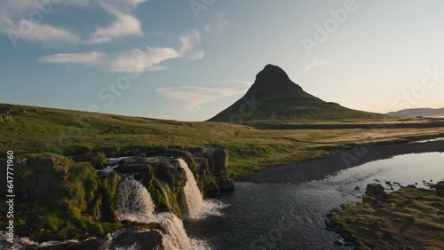 Sunrise over volcanic Kirkjufell mountain with waterfall flowing in summer at Iceland photo