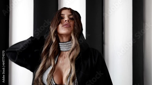 portrait of mysterious seductive woman with big breasts taking off black hood from her pretty face