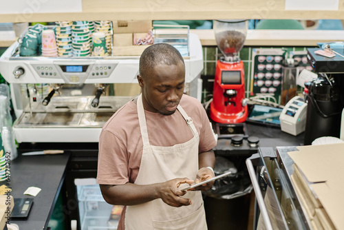 African American barman working online on digital tablet
