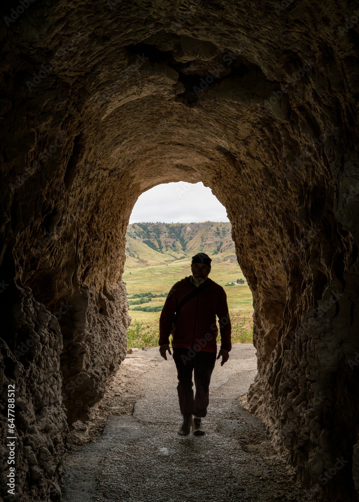 silhouette of a male hiker walking through a tunnel on the Saddle Rock Trail leading to the summit of Scotts Bluff National Monument silhouette of a male hiker walking through a tunnel on the Saddle Rock Trail leading to the summit of Scotts Bluff National Monument