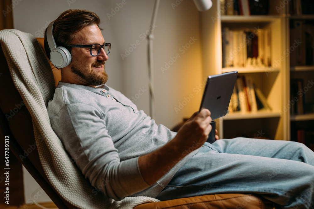 Smiling man using tablet in free time at home.