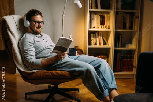 Caucasian man loves relaxing with a good book in the evening at home.