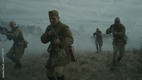 Slow motion tracking shot of male reenactors wearing Soviet Red Army uniforms performing offensive photo