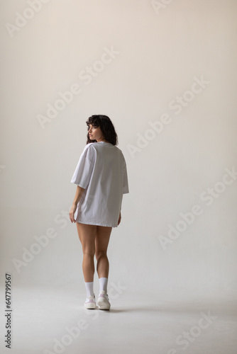 Attractive woman with curly hair in oversized t-shirt. Mock-up