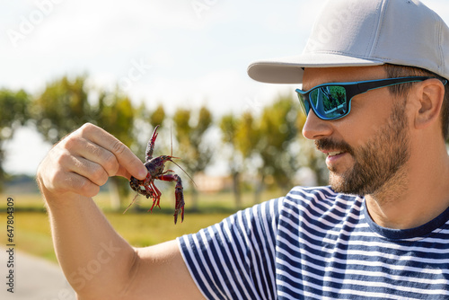A young man looks at a red swamp crayfish caught in a rice field in Albufera, Valencia, Spain