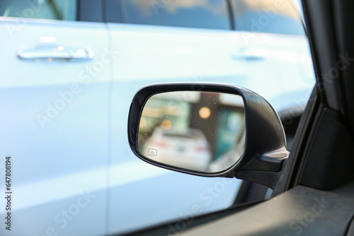 car's rearview mirror, reflecting a scenic road behind. The mirror symbolizes nostalgia, reflection, and the journey of life, capturing moments from the past © Your Hand Please