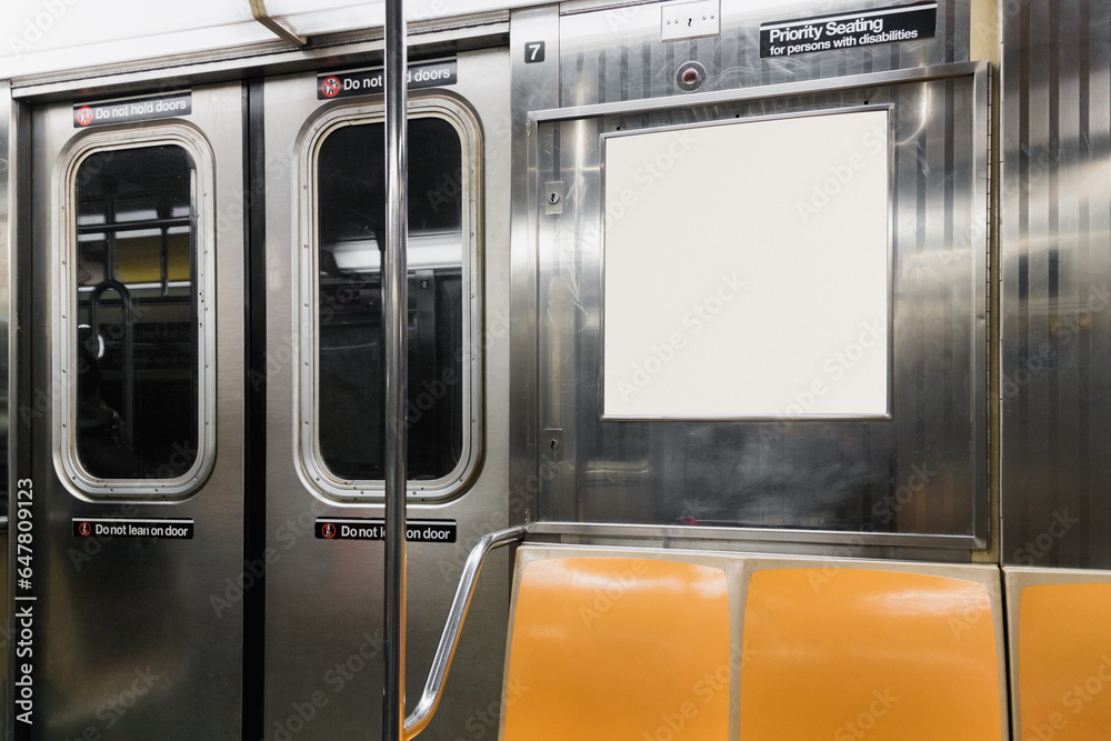 Interior view of a subway car in New York. There are yellow seats and a blank space for advertising signage.