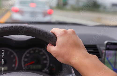 hand grips a car steering wheel, symbolizing safe and controlled driving, with a focus on responsibility and road safety